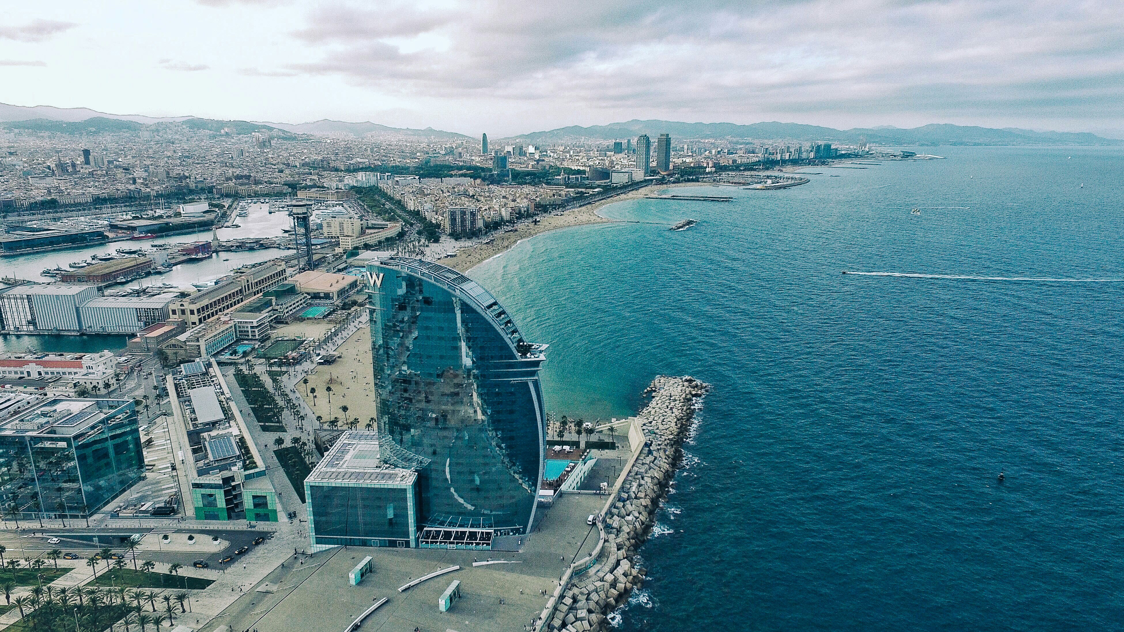Aerial view of Barcelona’s coastline and the W Hotel, showcasing the Mediterranean lifestyle and luxury property opportunities for buying a second home in Spain.