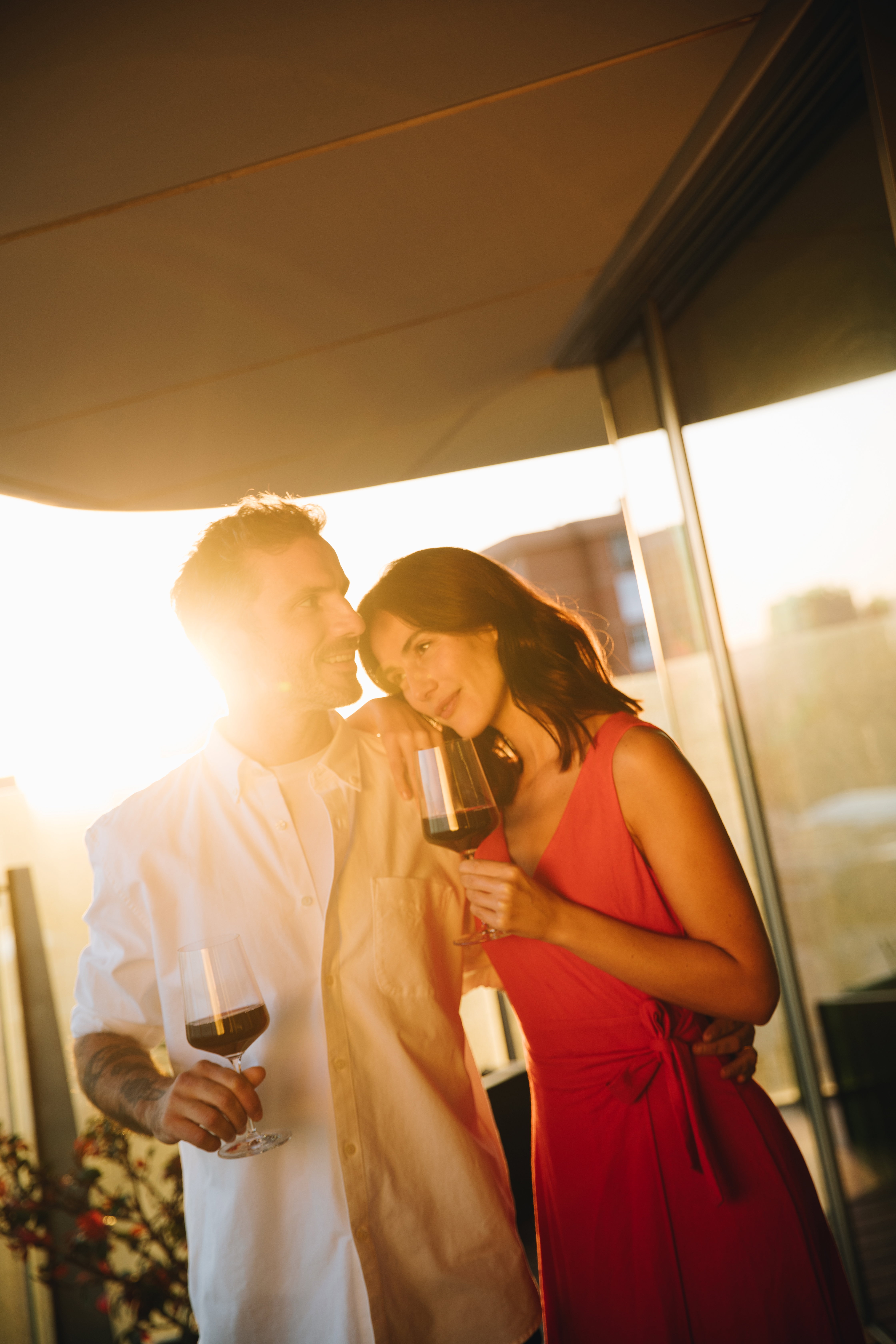 A couple holding wine glasses on a sunlit balcony at golden hour, exemplifying the luxury lifestyle associated with global wealth relocation to Barcelona.