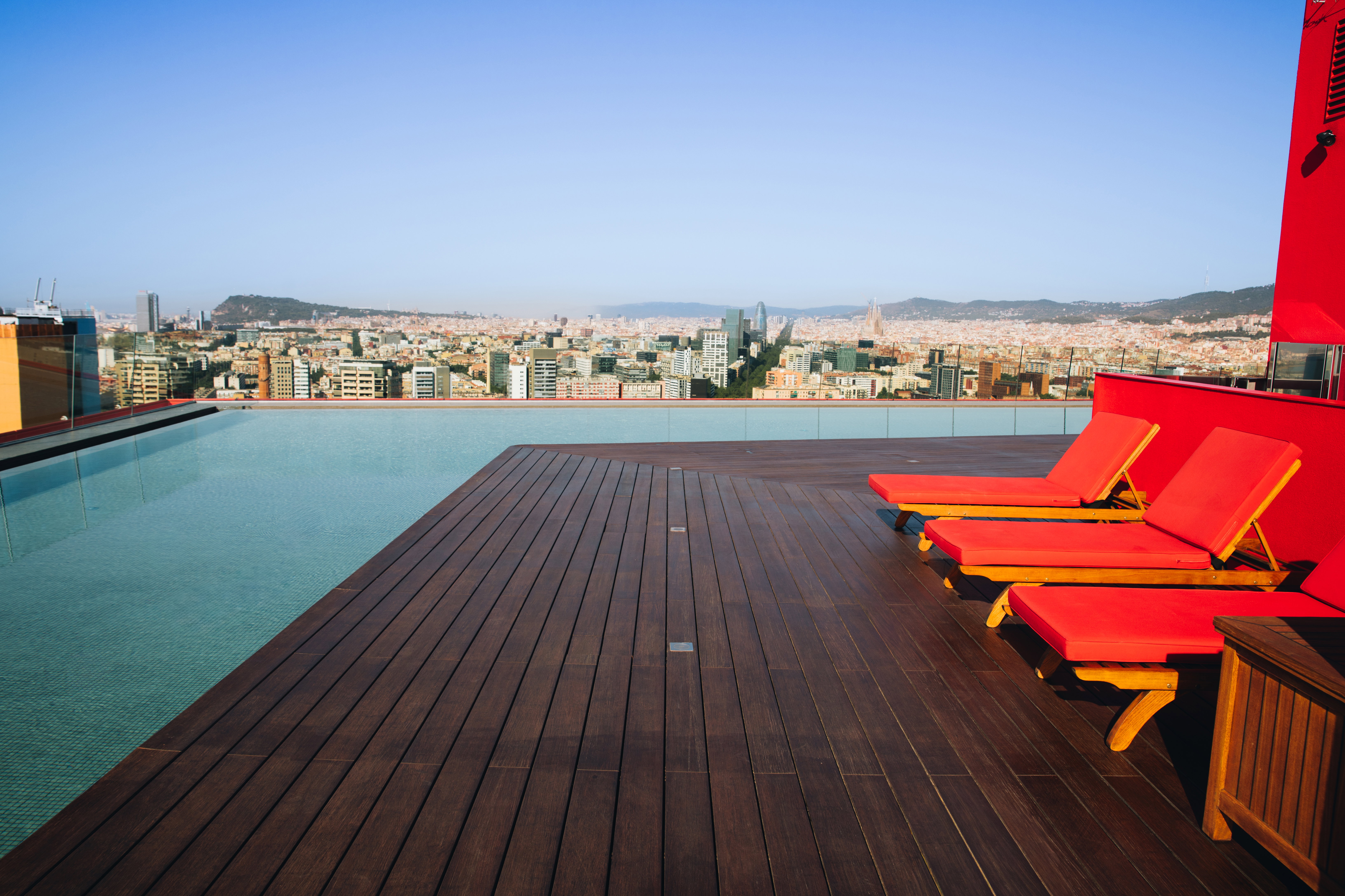 Rooftop infinity pool and sun loungers at Antares Barcelona overlooking the city skyline, representing luxury real estate capital appreciation in Barcelona's northern waterfront.