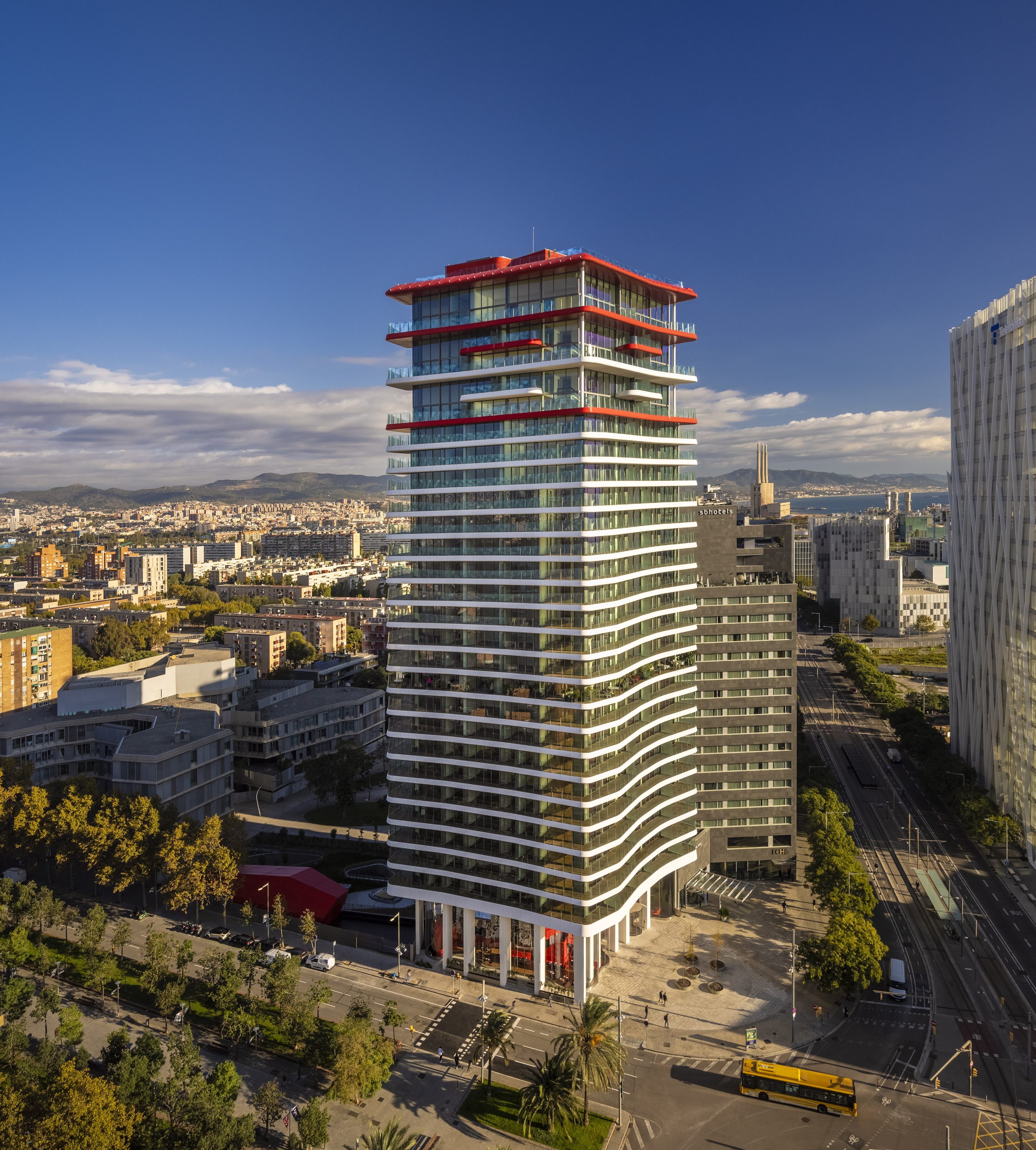 Aerial view of Antares Barcelona luxury residential tower with distinctive red rooftop accents, highlighting prime capital appreciation and urban regeneration along Barcelona's northern waterfront.