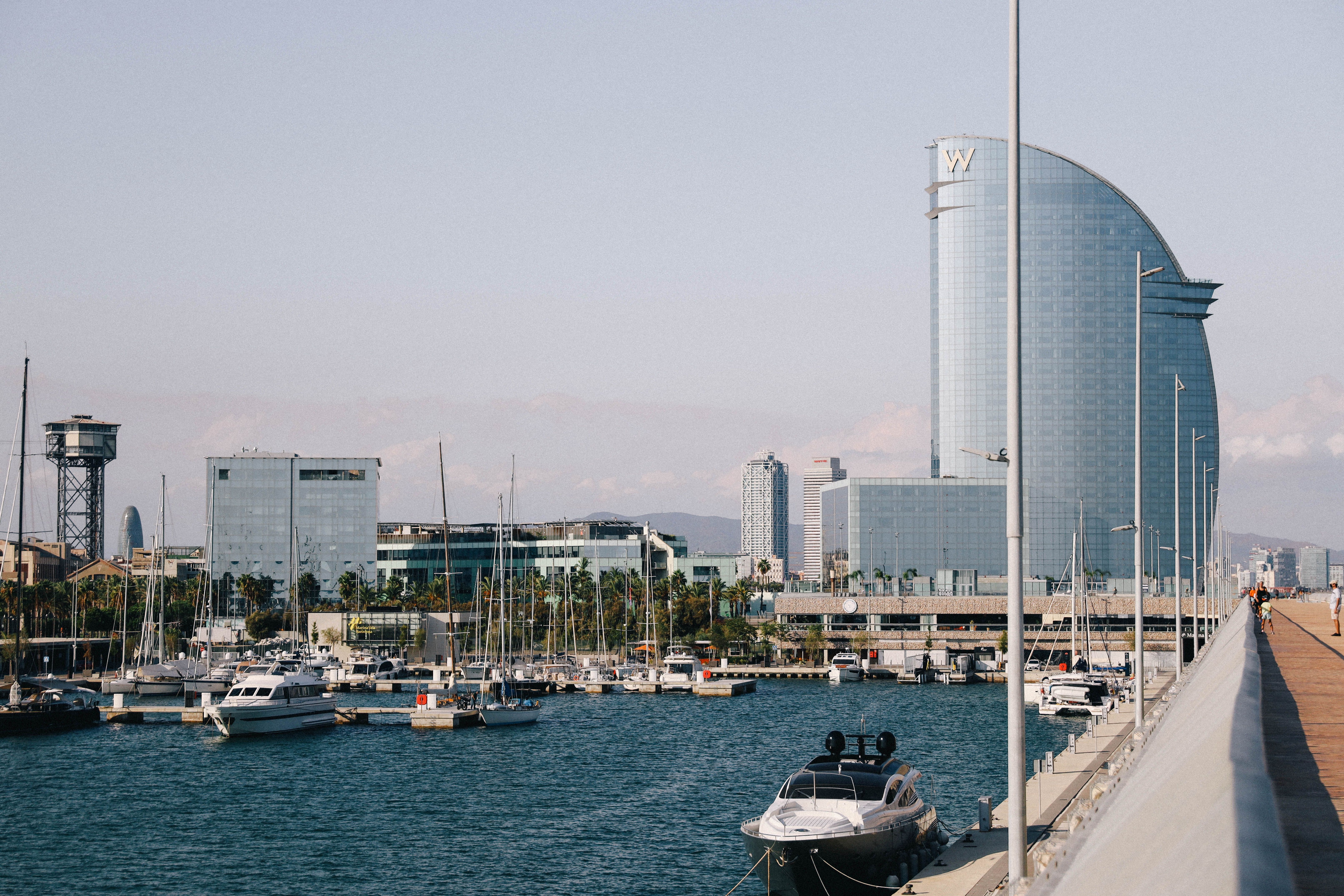Barcelona coastal harbor lined with yachts and the iconic sail-shaped W Barcelona hotel along the waterfront, illustrating long-term value creation and the durable water premium driving coastal capital appreciation.
